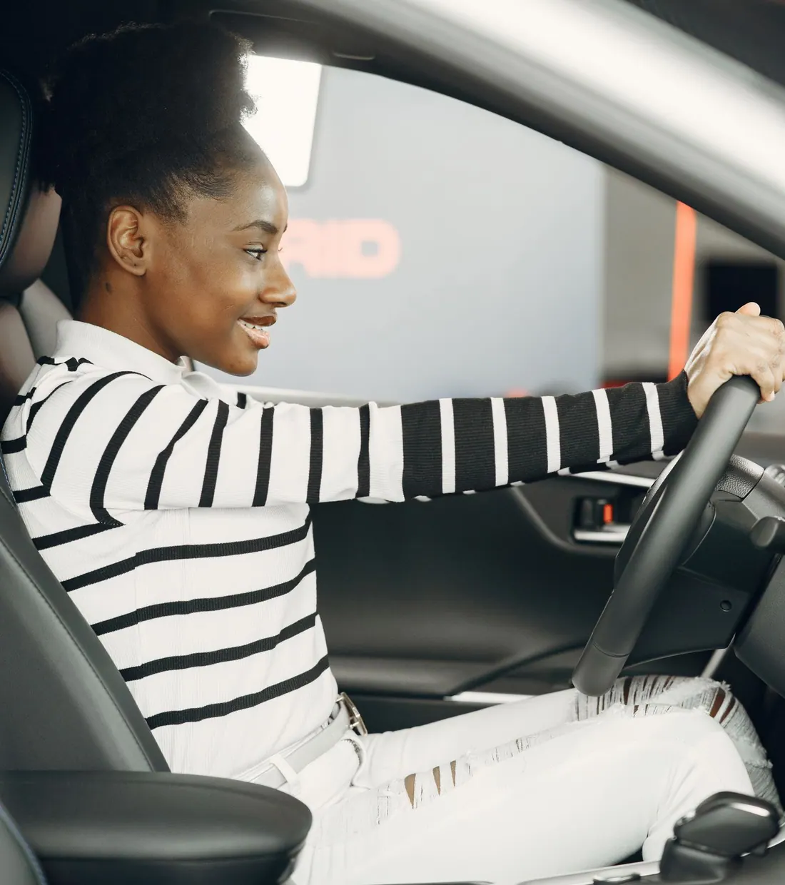 Aluna sorrindo ao volante durante uma aula de direção