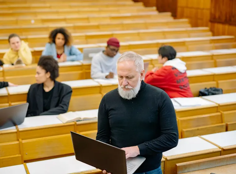 Adultos assistindo a uma aula em sala com anotações e notebooks